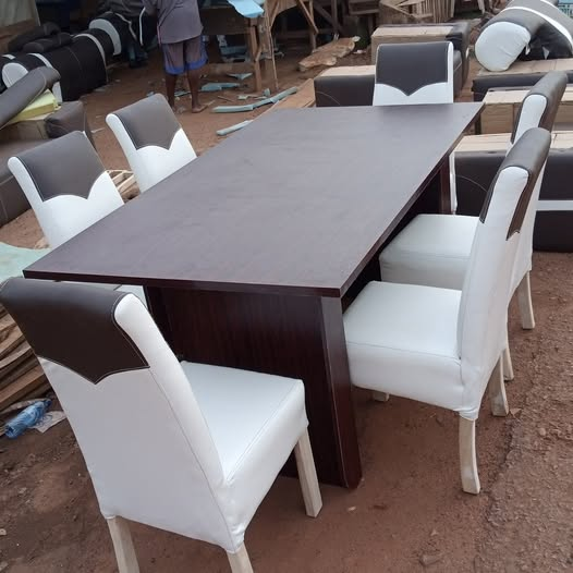 Dark wood dining table with black and white upholstered dining chairs shown at the workshop