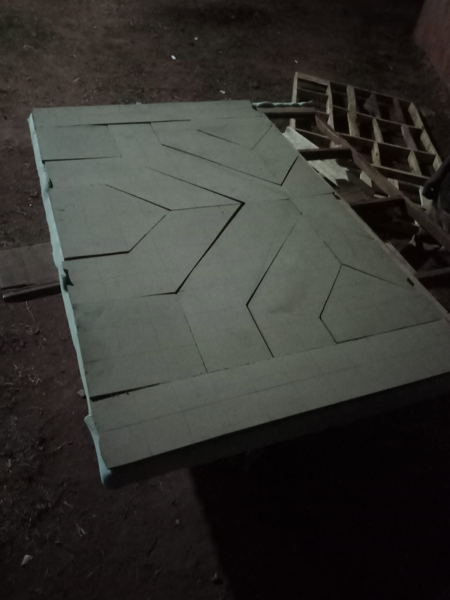 Cut geometric bed-headboard panels arranged on a full-size base in the workshop