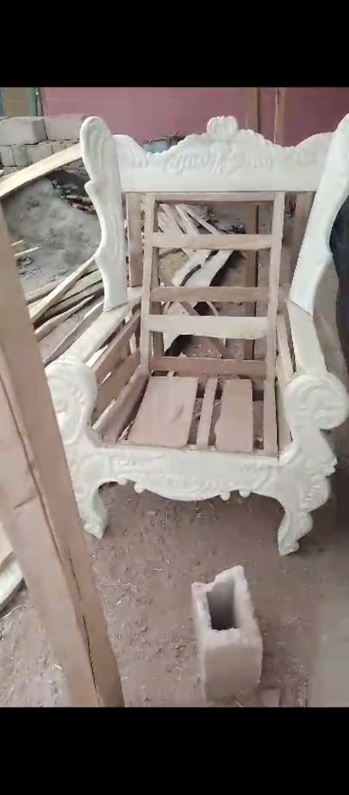 White carved wooden chair frame with open seat slats at the workshop