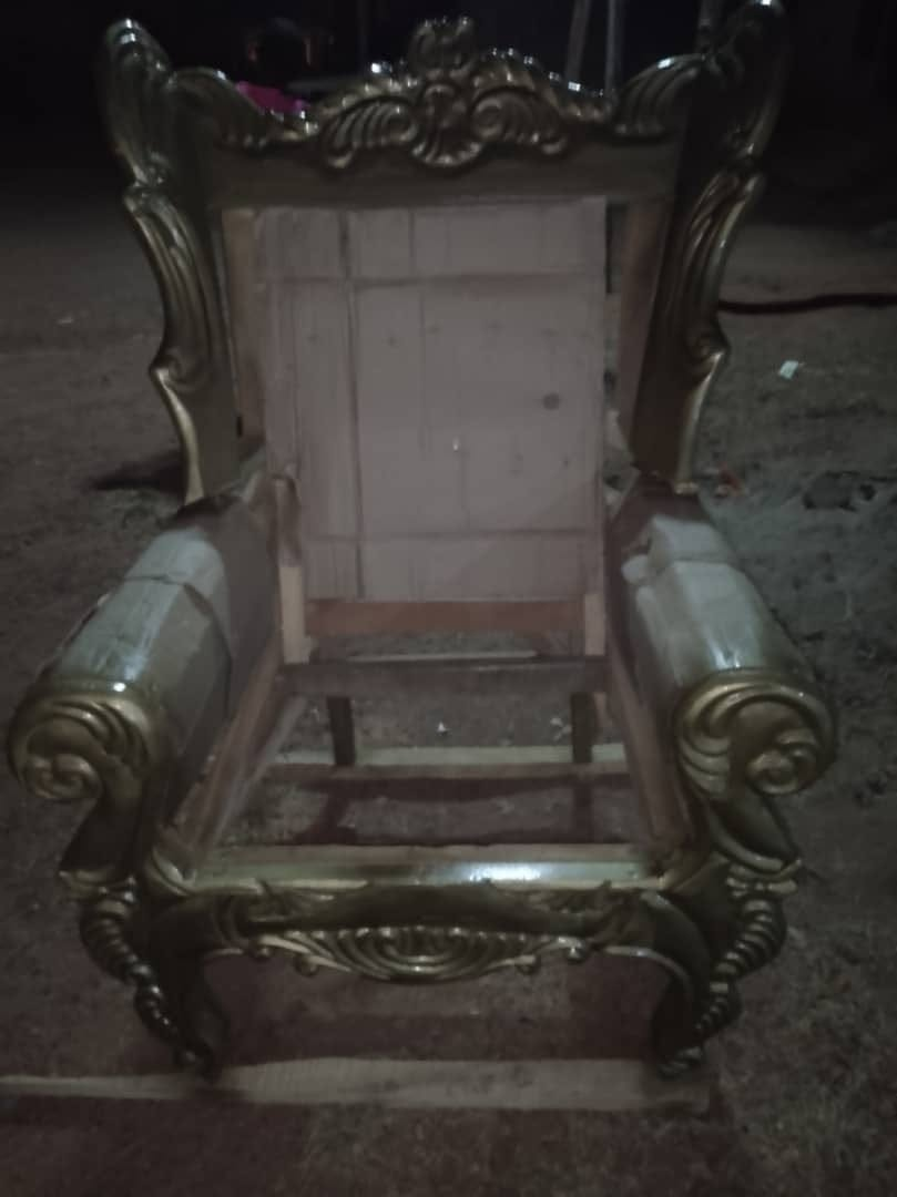 Gold carved wooden armchair frame with open upholstered seat area at the workshop
