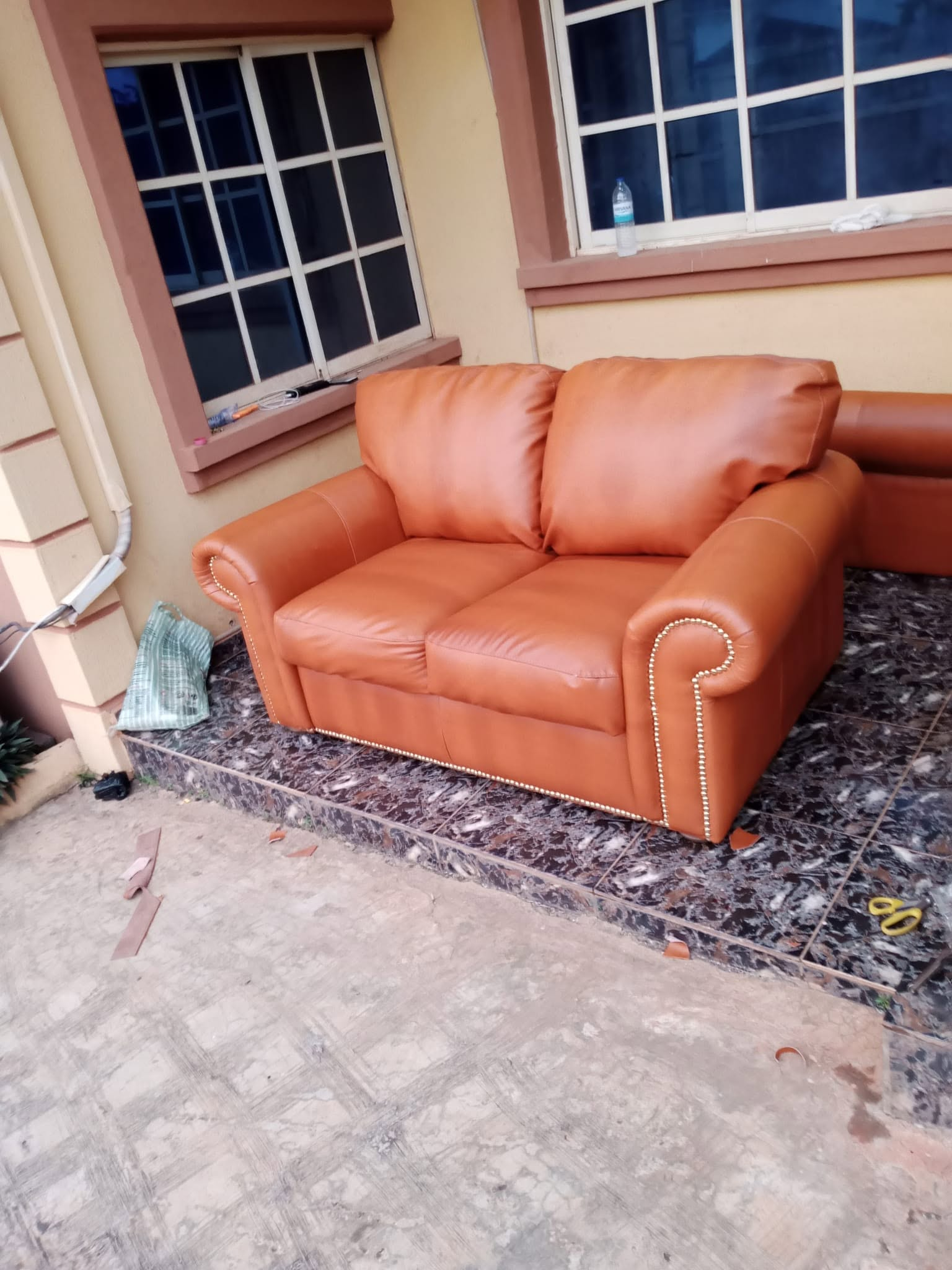 Caramel upholstered sofa bed shown as finished seating on a tiled veranda