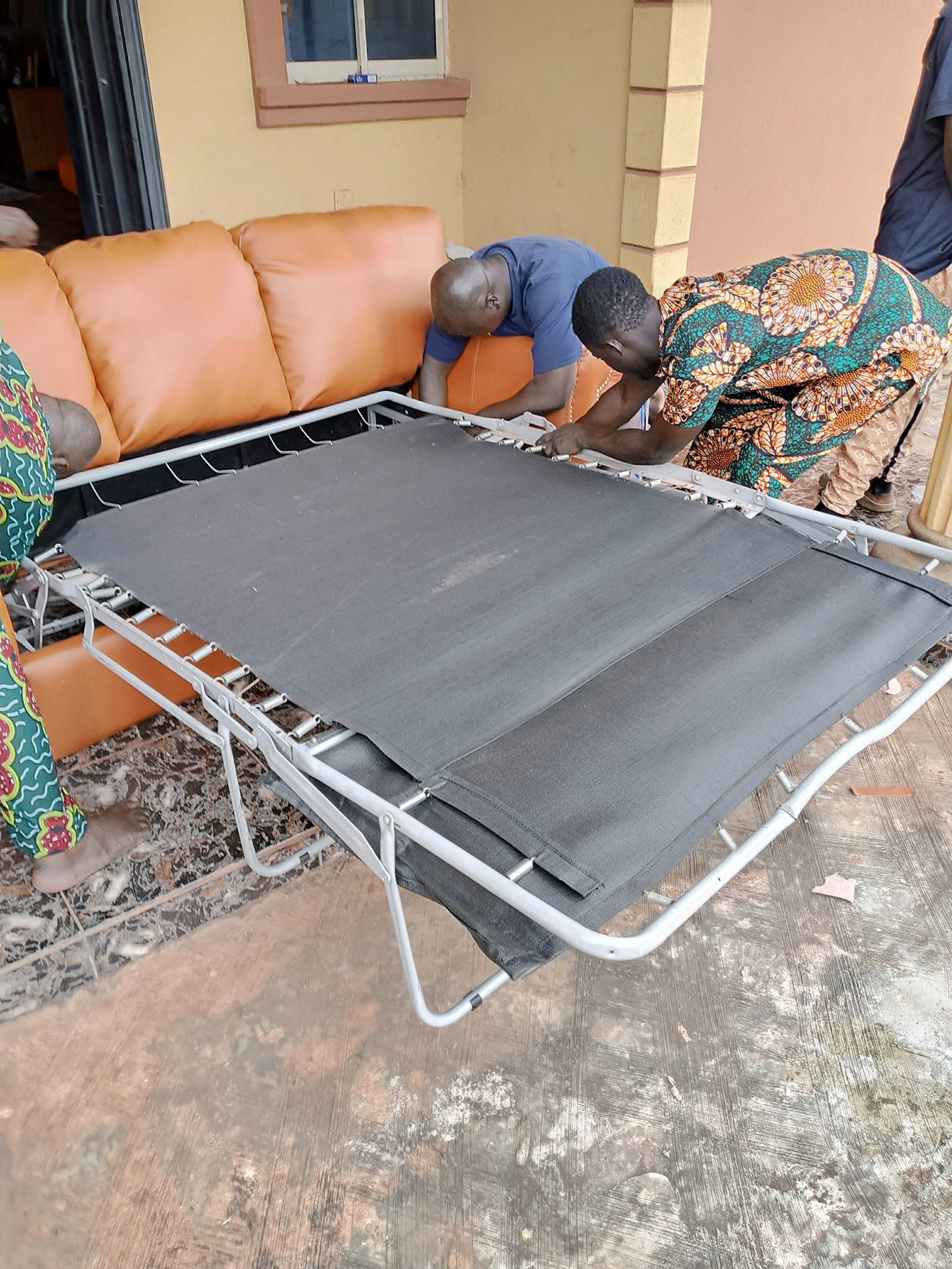 People positioning a metal pull-out mechanism in front of caramel upholstered seating