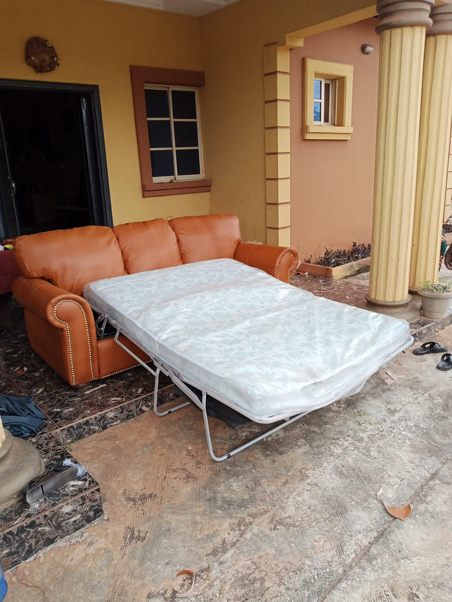 Caramel upholstered sofa bed shown open with a mattress on its pull-out section
