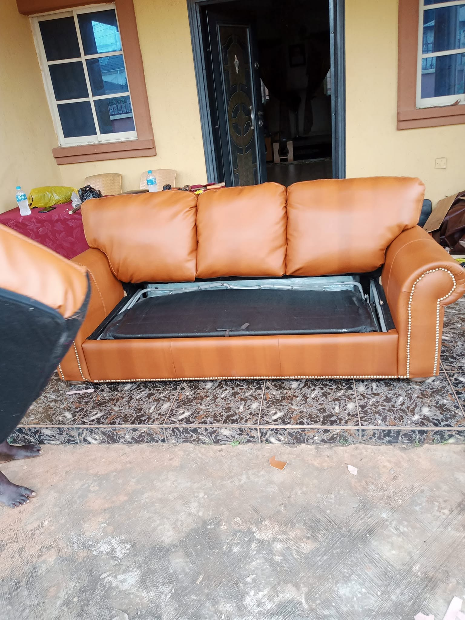 Caramel upholstered sofa with the pull-out mechanism visible inside the base
